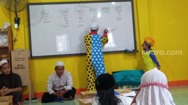 Ustaz Yahya Edward Hendrawan ditemani putranya, Bocil, berpenampilan ala badut saat mengajar ngaji bocah-bocah Panti Asuhan Darussalam, Pinang, Kota Tangerang. [SuaraJakarta.id/Muhammad Jehan Nurhakim]