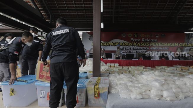 Penyidik Dirtipid Narkoba Bareskrim Polri menata barang bukti sabu sebelum gelar kasus jaringan internasional di Lapangan Bhayangkara Mabes Polri, Jakarta, Rabu (28/4/2021). [Suara.com/Angga Budhiyanto]