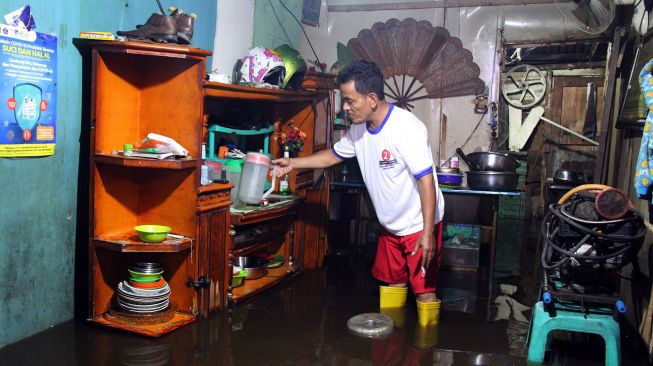 Seorang warga menyelamatkan barang-barang miliknya saat banjir besar pasang air laut (rob) di Kota Dumai, Riau, Rabu (28/4/2021). ANTARA FOTO/Aswaddy Hamid

