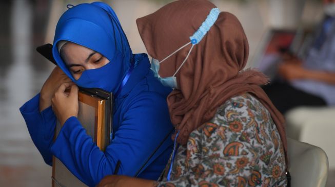 Keluarga korban tenggelamnya KRI Nanggala 402 memeluk foto suaminya yang merupakan prajurit KRI Nanggala-402 yang gugur dalam musibah tenggelamnya kapal selam tersebut di perairan Bali saat Penganugerahan tanda kehormatan dan kenaikan pangkat luar biasa prajurit KRI Nanggala-402 di Pusat Penerbangan TNI Angkatan Laut, SIdoarjo, Jawa Timur, Kamis (29/4/2021). ANTARA FOTO/Zabur Karuru