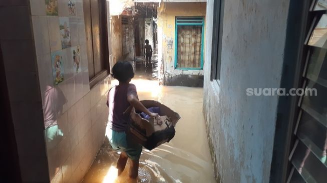 Warga Kebon Pala Kampung Melayu saat merapihkan barang-barang karena banjir. (Suara.com/Yaumal)