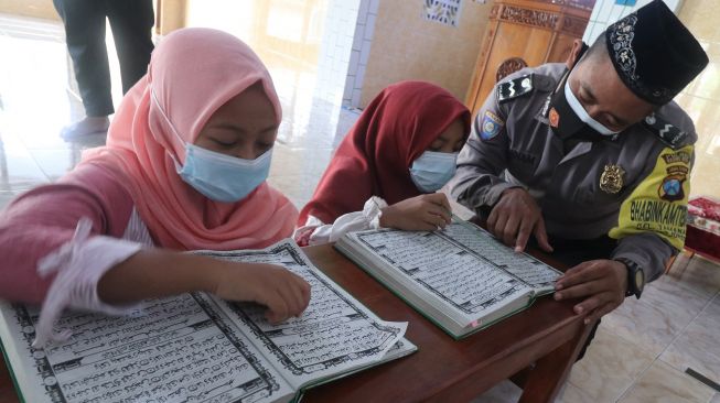 Polisi Aipda Syaiful Annam (kanan) mengajar anak-anak membaca Al Quran di Masjid An-Nuur, Kelurahan Tamanan, Kota Kediri, Jawa Timur, Kamis (29/4/2021).  ANTARA FOTO/Prasetia Fauzani