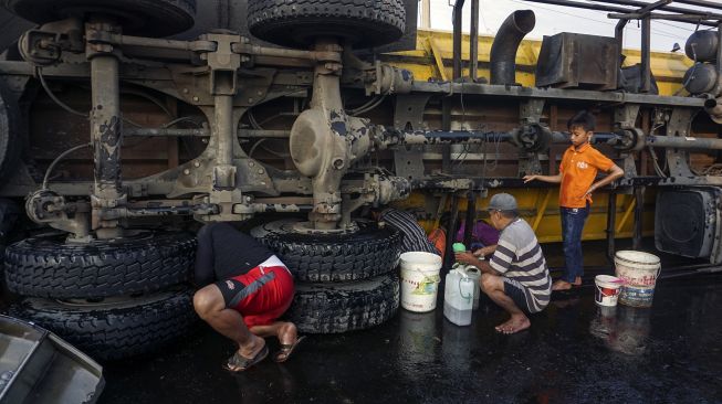 Warga mengambil minyak dari sebuah truk tangki yang mengalami kecelakaan di Jalur Pantura Sipait, Kabupaten Pekalongan, Jawa Tengah, Kamis (29/4/2021). ANTARA FOTO/Harviyan Perdana Putra