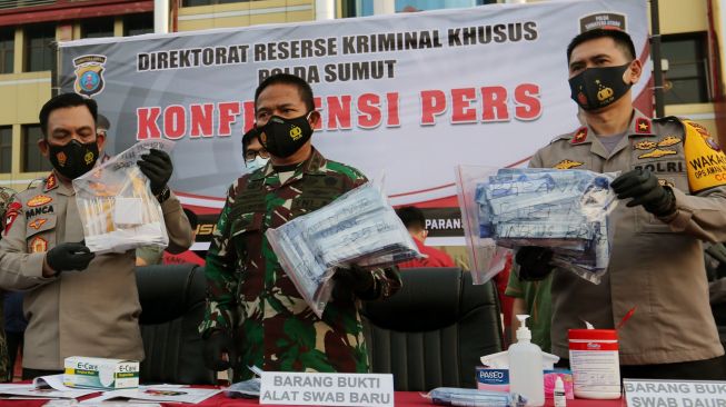 Kapolda Sumatera Utara Irjen Pol Panca Putra Simanjuntak (kiri), Pangdam I/Bukit Barisan Mayjen TNI Hassanudin (tengah) dan Waka Polda Brigjen Pol Dadang Hartanto (kanan) menunjukan barang bukti alat swab tes cepat antigen bekas saat rilis kasus di Polda Sumatera Utara, Medan, Sumatera Utara, Kamis (29/4/2021).  ANTARA FOTO/Adiva Niki