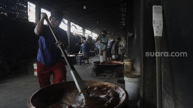 Pekerja mengaduk adonan dodol Betawi di Pondok Dodol Sari Rasa Ibu Yuyun di kawasan Pasar Minggu, Jakarta Selatan, Jumat (30/4/2021). [Suara.com/Angga Budhiyanto]