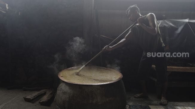 Pekerja mengaduk adonan dodol Betawi di Pondok Dodol Sari Rasa Ibu Yuyun di kawasan Pasar Minggu, Jakarta Selatan, Jumat (30/4/2021). [Suara.com/Angga Budhiyanto]