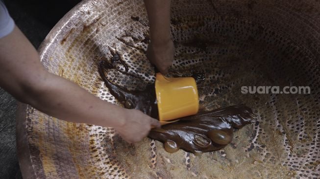 Pekerja menyelesaikan proses pembuatan dodol Betawi di Pondok Dodol Sari Rasa Ibu Yuyun di kawasan Pasar Minggu, Jakarta Selatan, Jumat (30/4/2021). [Suara.com/Angga Budhiyanto]