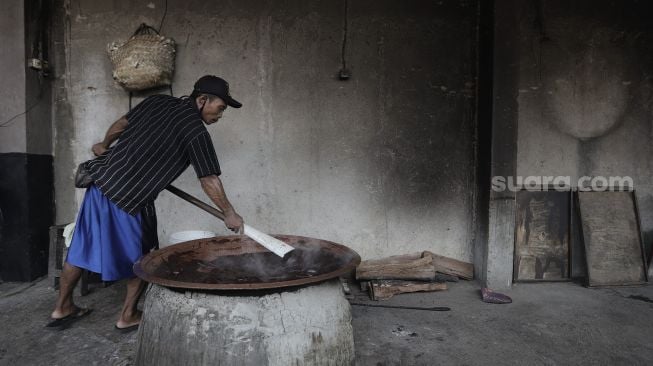 Pekerja mengaduk adonan dodol Betawi di Pondok Dodol Sari Rasa Ibu Yuyun di kawasan Pasar Minggu, Jakarta Selatan, Jumat (30/4/2021). [Suara.com/Angga Budhiyanto]