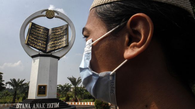 Warga melintas di depan tugu Al Quran di Masjid Istana Anak Yatim, Desa Cikeas Udik, Gunung Putri, Kabupaten Bogor, Jawa Barat, Jumat (30/4/2021).  ANTARA FOTO/Yulius Satria Wijaya
