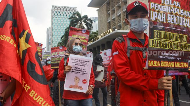 Dokumentasi - Aliansi buruh melakukan aksi unjuk rasa dengan membawa poster berisi tuntutan kepada pemerintah saat memperingati hari buruh sedunia atau May Day di Jakarta, Sabtu (1/5/2021). [Suara.com/Alfian Winanto]