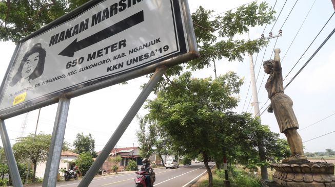 Pengendara sepeda motor melintas di depan patung pejuang buruh Marsinah sebagai petunjuk arah makam di Desa Nglundo, Nganjuk, Jawa Timur, Sabtu (1/5/2021). ANTARA FOTO/Prasetia Fauzani