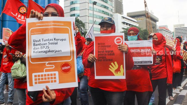 Aliansi buruh melakukan aksi unjuk rasa dengan membawa poster berisi tuntutan kepada pemerintah saat memperingati hari buruh sedunia atau May Day di Jakarta, Sabtu (1/5/2021). [Suara.com/Alfian Winanto]