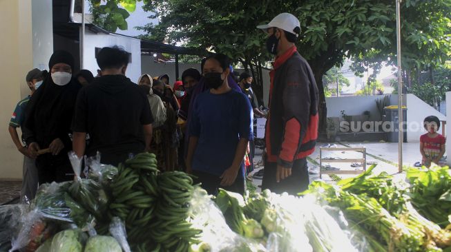 Warga mengantre untuk mengambil sayuran saat kegiatan bazar sayuran gratis di Masjid Ar Ruhama, Jati Padang, Jakarta, Minggu (2/5/2021). [Suara.com/Dian Latifah]