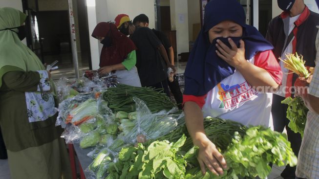 Warga mengambil sayuran saat kegiatan bazar sayuran gratis di Masjid Ar Ruhama, Jati Padang, Jakarta, Minggu (2/5/2021). [Suara.com/Dian Latifah]