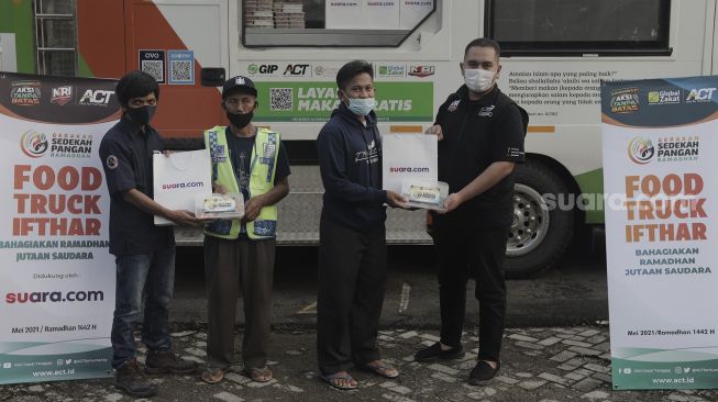 Redaktur Pelaksana Suara.com, Arsito Hidayatullah (kiri) bersama dengan Kepala Cabang ACT (Aksi Cepat Tanggap) Kota Bekasi, Rizky Renanda (kanan) memberikan bantuan makanan kepada warga untuk berbuka puasa di Masjid Husnul Khatimah, Jatiasih, Kota Bekasi, Minggu (2/5/2021). [Suara.com/Angga Budhiyanto]