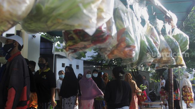 Warga mengantre untuk mengambil sayuran saat kegiatan bazar sayuran gratis di Masjid Ar Ruhama, Jati Padang, Jakarta, Minggu (2/5/2021). [Suara.com/Dian Latifah]