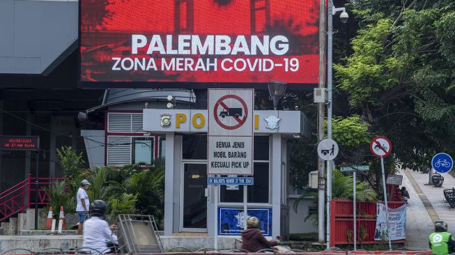 Pengendara melintas di Jalan Jenderal Sudriman dengan latar videotron bertuliskan Palembang zona merah COVID-19 di Palembang, Sumatera Selatan, Senin (3/5/2021).  ANTARA FOTO/Nova Wahyudi