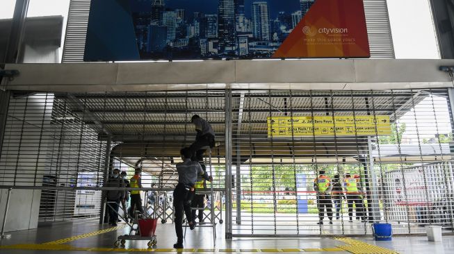 Petugas kebersihan menutup pagar Stasiun Tanah Abang, di Jakarta, Senin (3/5/2021). ANTARA FOTO/Galih Pradipta