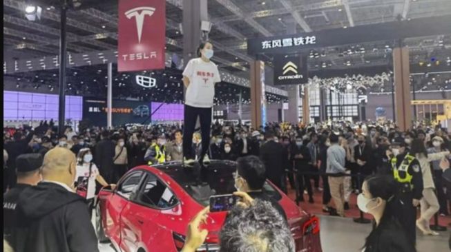 Aksi protes wanita terhadap Tesla dengan menaiki atap mobi saat acara Shanghai Auto Show (SCMP)