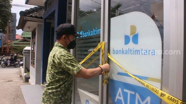 Petugas usai mengecek kondisi ATM Bankaltimtara yang dibongkar paksa, di Jalan Pangeran Antrasari Kota Samarinda, Selasa (4/5/2021). [Istimewa/SuaraKaltim.id]