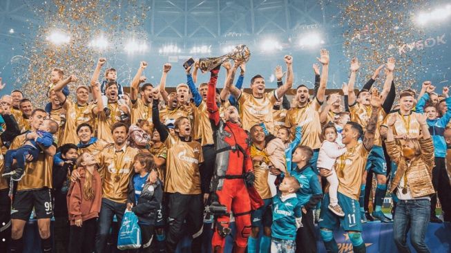 Pemain Zenit Saint Petersburg menyamar jadi Deadpool saat mengangkat trofi juara Liga Rusia. (Twitter/@Russia)