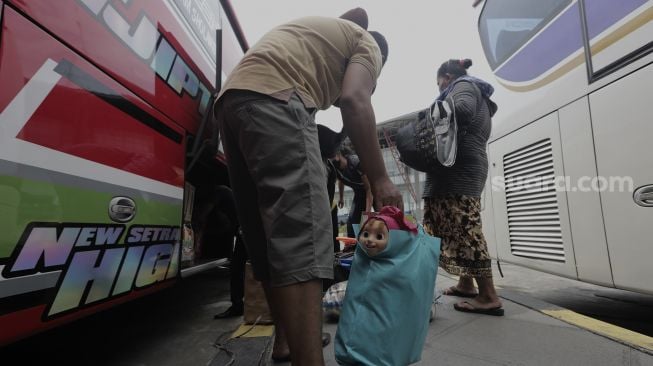 Sejumlah calon penumpang memasukkan barang bawaanya ke dalam bagasi bus di Terminal Pulo Gebang, Jakarta Timur, Selasa (4/5/2021). [Suara.com/Angga Budhiyanto]