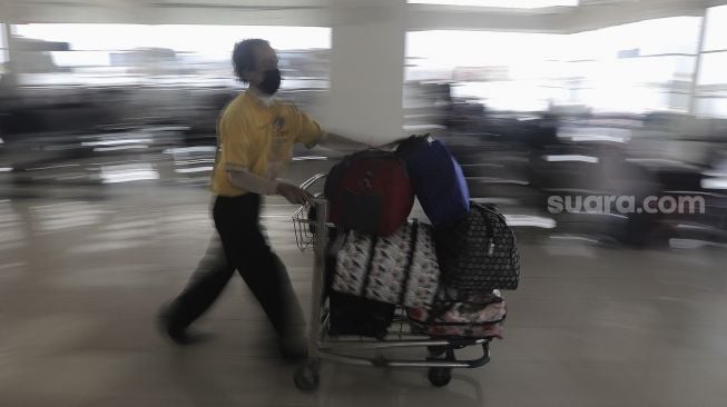 Porter membawakan barang bawaan calon penumpang di Terminal Pulo Gebang, Jakarta Timur, Selasa (4/5/2021). [Suara.com/Angga Budhiyanto]