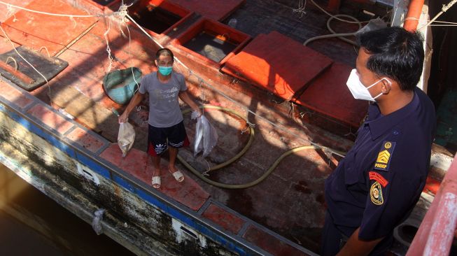 Seorang petugas menyaksikan nelayan memperlihatkan ikan hasil tangkapan kapal ikan asing berbendera Vietnam dengan nomor lambung KG 5090 TS di dermaga Stasiun Pengawasan Sumber Daya Kelautan dan Perikanan (PSDKP) Pontianak di Kabupaten Kubu Raya, Kalimantan Barat, Selasa (4/5/2021). ANTARA FOTO/Jessica Helena Wuysang