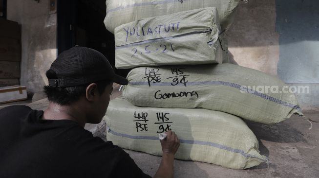 Pekerja menuliskan alamat pada barang yang akan dikirim via jasa ekspedisi kereta api di Jalan Bungur Raya, Senen, Jakarta, Selasa (4/5/2021). [Suara.com/Angga Budhiyanto]