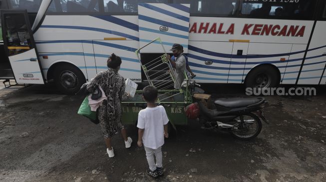 Penyedia jasa layanan angkut barang membantu memasukkan barang bawaan calon penumpang ke dalam bagasi bus di Terminal Lebak Bulus, Jakarta, Rabu (5/5/2021). [Suara.com/Angga Budhiyanto]