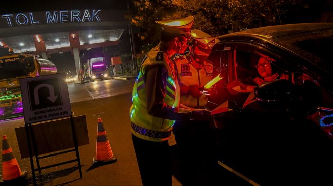 Petugas kepolisian memeriksa dokumen pengendara yang melintas dari arah Jakarta menuju pulau Sumatera melalui Pelabuhan Merak di pintu Gerbang Tol Merak, Banten, Kamis (6/5/2021) dini hari. ANTARA FOTO/Galih Pradipta