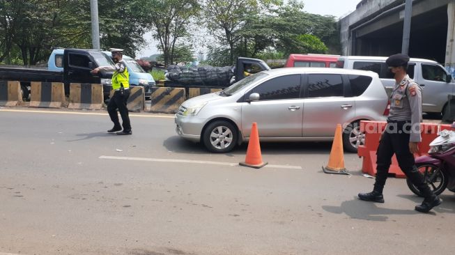 Polisi menghalau dan memeriksa kendaraan di pos penyekatan exit Tol Bitung, [Suara.com/Wivy]