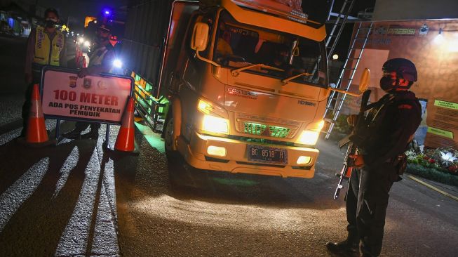 Petugas kepolisian memeriksa dokumen penumpang bus yang melintas dari arah Jakarta menuju pulau Sumatera melalui Pelabuhan Merak di pintu Gerbang Tol Merak, Banten, Kamis (6/5/2021) dini hari. ANTARA FOTO/Galih Pradipta
