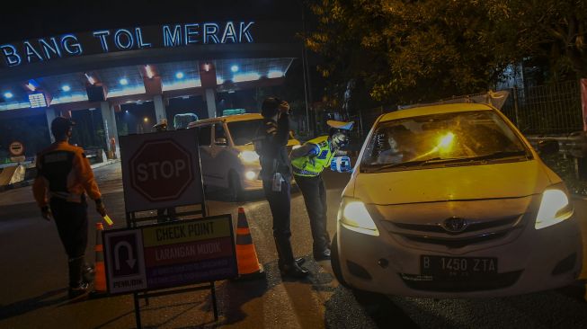 Petugas kepolisian memeriksa dokumen penumpang bus yang melintas dari arah Jakarta menuju pulau Sumatera melalui Pelabuhan Merak di pintu Gerbang Tol Merak, Banten, Kamis (6/5/2021) dini hari. ANTARA FOTO/Galih Pradipta