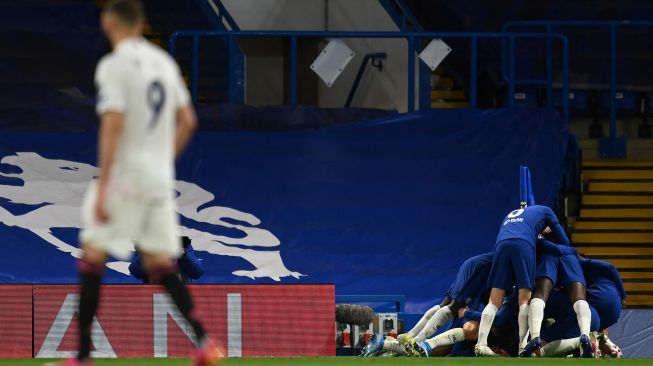 Penyerang Real Madrid Karim Benzema (kiri) bereaksi ketika gelandang Chelsea, Mason Mount dikerumuni rekan satu timnya setelah mencetak gol kedua selama pertandingan sepak bola semifinal leg kedua Liga Champions antara Chelsea melawan Real Madrid di Stamford Bridge,  Kamis (6/5/2021) dini hari WIB.Glyn KIRK / AFP