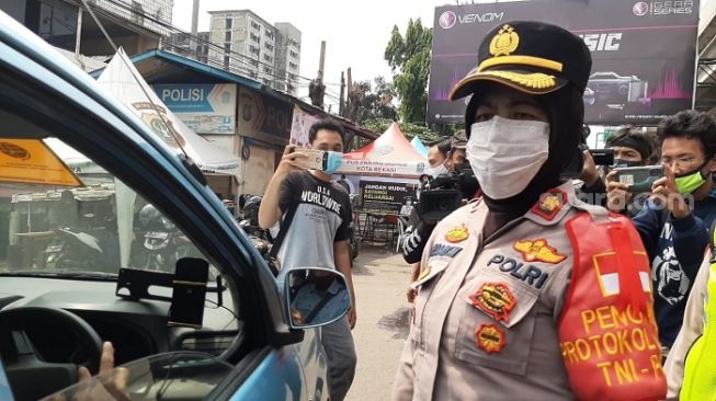 Polwan saat memberhentikan mobil taksi yang penuh penumpang di posko penyekatan mudik di kawasan Kalimalang, Bekasi. (Suara.com/Ummi HS)