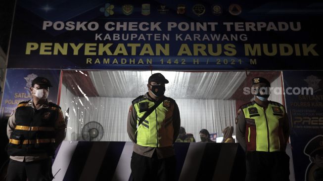 Petugas gabungan bersiap mengatur arus lalu lintas saat hari pertama penyekatan larangan mudik di pos penyekatan Tanjungpura, Karawang, Jawa Barat, Kamis (6/5/2021). [Suara.com/Angga Budhiyanto]