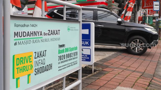 Papan informasi pemberitahuan zakat secara drive thru terpasang di Masjid Nurul Hidayah, Tanah Kusir, Jakarta Selatan, Sabtu (8/5/2021). [Suara.com/Alfian Winanto]