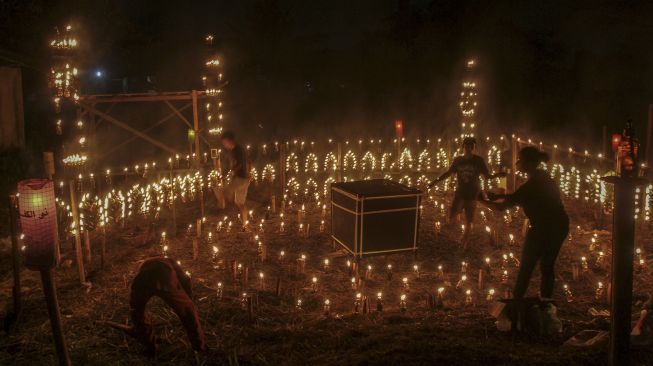 Warga menyalakan lentera yang digantung pada 'Lampu Colok' berbentuk miniatur bangunan Kabah dalam Festival Lampu Colok di Pekanbaru, Riau, Sabtu (8/5/2021). [ANTARA FOTO/Rony Muharrman]