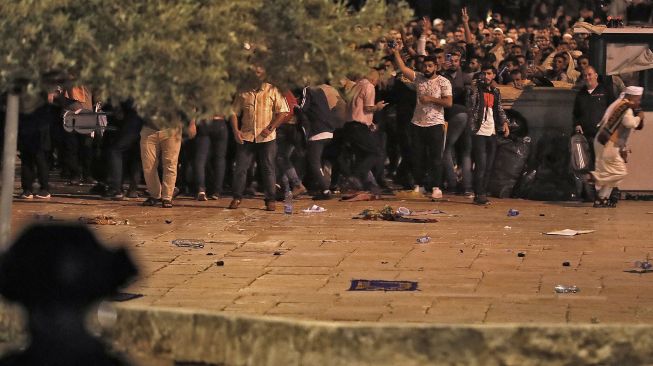 Warga Palestina bereaksi ketika polisi Israel menembakkan granat setrum selama bentrokan di kompleks Masjid Al Aqsa, di  Yerusalem, (7/5/2021).  Ahmad GHARABLI / AFP
