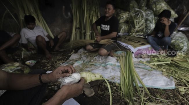 Pedagang menyelesaikan pembuatan kulit ketupat di Pasar Palmerah, Jakarta, Minggu (9/5/2021). [Suara.com/Angga Budhiyanto]