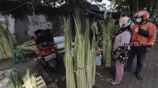 Pedagang melayani pembeli janur di Pasar Palmerah, Jakarta, Minggu (9/5/2021). [Suara.com/Angga Budhiyanto]