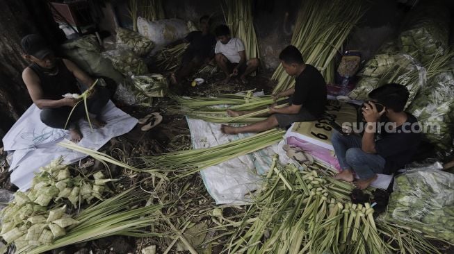 Pedagang menyelesaikan pembuatan kulit ketupat di Pasar Palmerah, Jakarta, Minggu (9/5/2021). [Suara.com/Angga Budhiyanto]