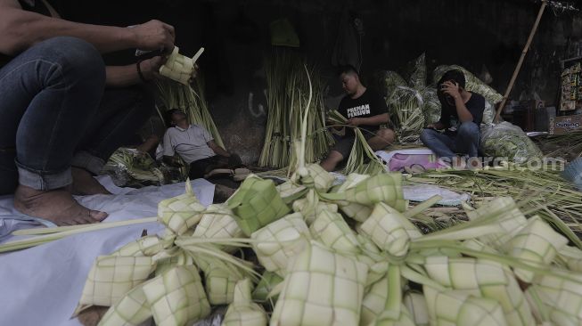 Pedagang menyelesaikan pembuatan kulit ketupat di Pasar Palmerah, Jakarta, Minggu (9/5/2021). [Suara.com/Angga Budhiyanto]