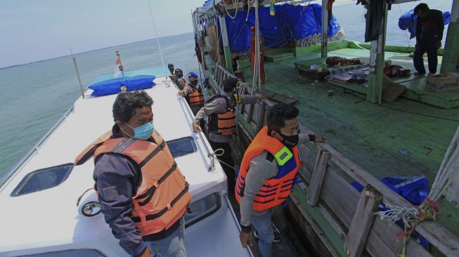 Personel Polair Polres Indramayu memeriksa kapal nelayan saat melakukan penyekatan jalur laut di perairan Indramayu, Jawa Barat, Minggu (9/5/2021). [ANTARA FOTO/Dedhez Anggara]