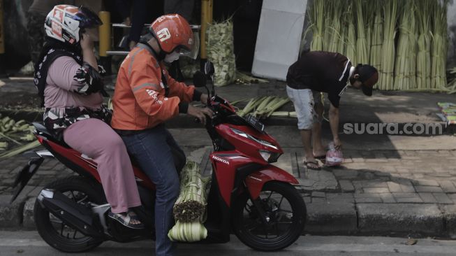 Warga bergegas pergi usai membeli janur di Pasar Palmerah, Jakarta, Minggu (9/5/2021). [Suara.com/Angga Budhiyanto]