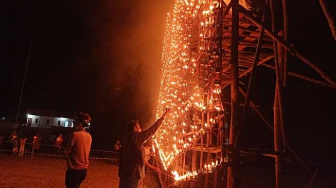 Para remaja saat menghidupkan api dari botol dan sumbu yang sudah disusun dalam tradisi lampu colok Bengkalis. [Suara.com/Panji Ahmad Syuhada]