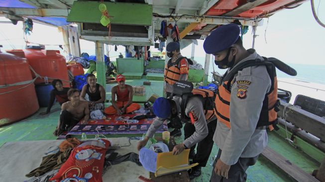 Personel Polair Polres Indramayu memeriksa data Anak Buah Kapal (ABK) nelayan saat melakukan penyekatan jalur laut di perairan Indramayu, Jawa Barat, Minggu (9/5/2021). [ANTARA FOTO/Dedhez Anggara]