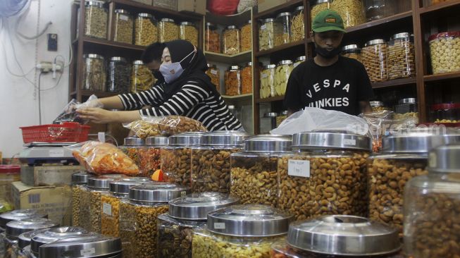 Pedagang melayani pembeli kue kering di Pasar Mester Jatinegara, Jakarta, Minggu (9/5/2021). [Suara.com/Dian Latifah]