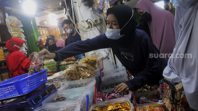 Pembeli memilih kue kering di Pasar Mester Jatinegara, Jakarta, Minggu (9/5/2021). [Suara.com/Dian Latifah]